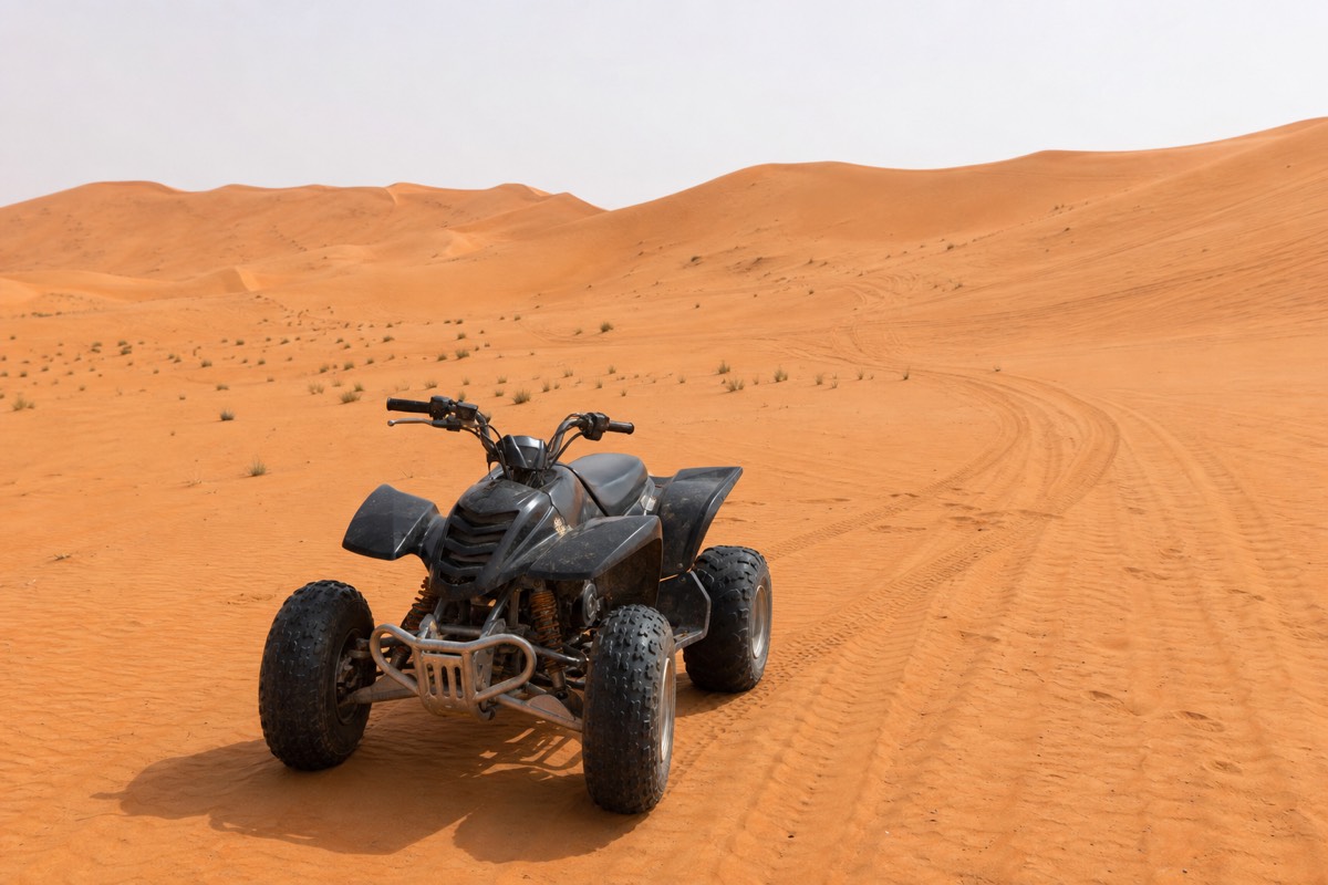 A quad bike parked on a Wahiba Sands dune with tracks curving across the sand